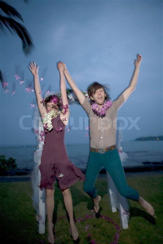 Bride and groom jumping for joy, Big Island, Hawaii, USA, stock photo