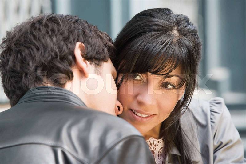 A young man whispering to a woman, stock photo