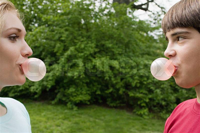 Teenage couple blowing bubble gum bubbles, stock photo