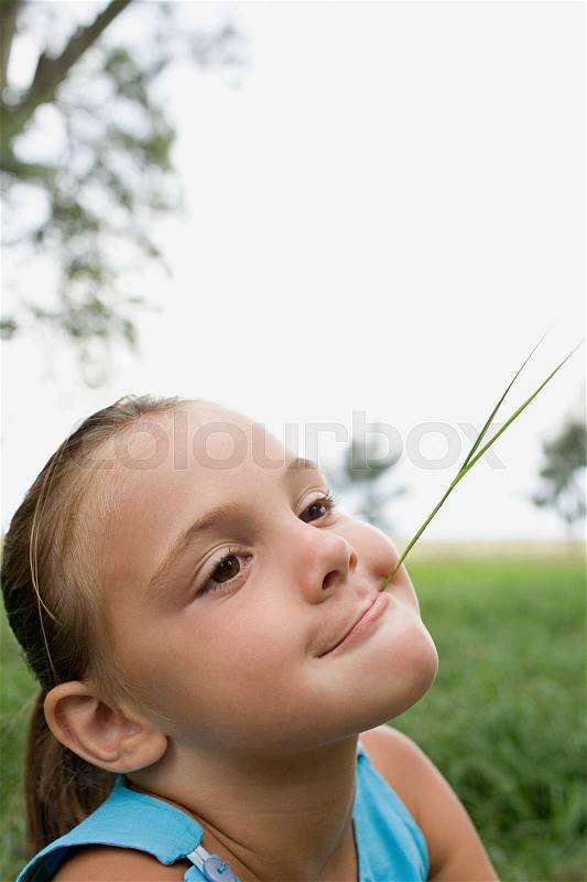 Girl with a piece of straw in her mouth, stock photo