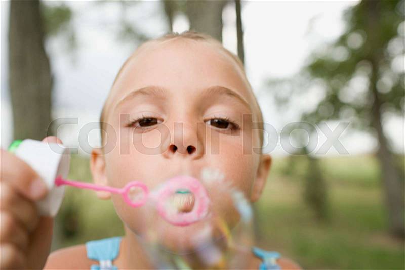 Girl using a bubble wand, stock photo
