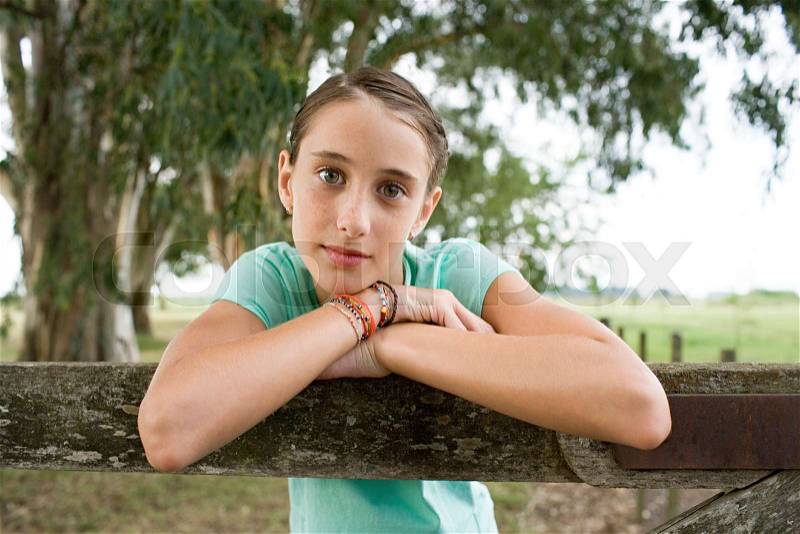 Girl leaning on a wooden fence, stock photo