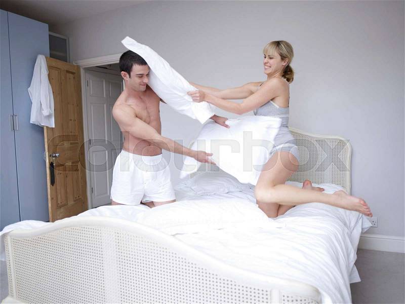 Man and woman bedroom pillow fight, stock photo