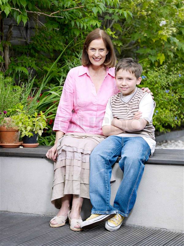 Mum and son sitting on patio in garden, stock photo