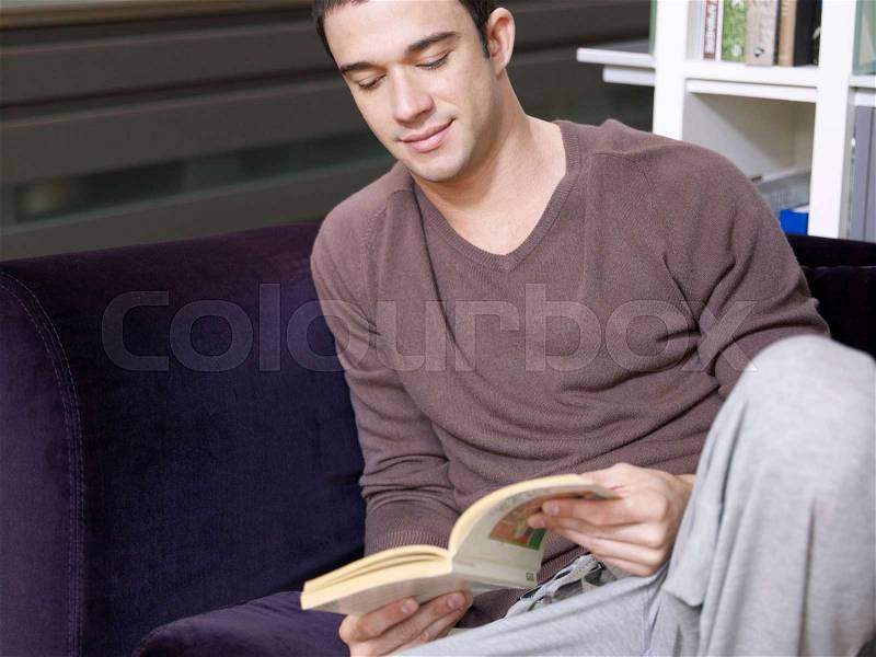 Young man sitting relaxed and reading, stock photo