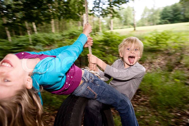 Boy and girl on tire swing, stock photo