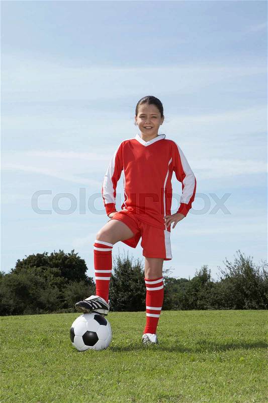 Female footballer standing with ball, stock photo