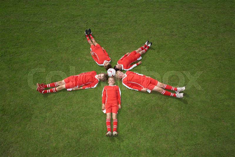 Footballers lying around a ball, stock photo