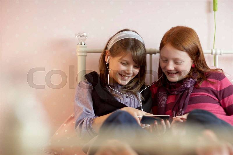 Teenage girls sharing music player, stock photo