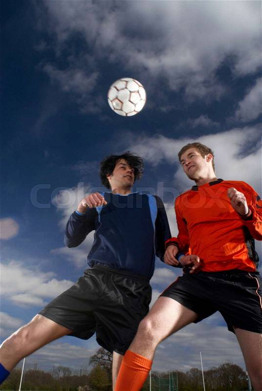 Two footballers jumping for football, stock photo