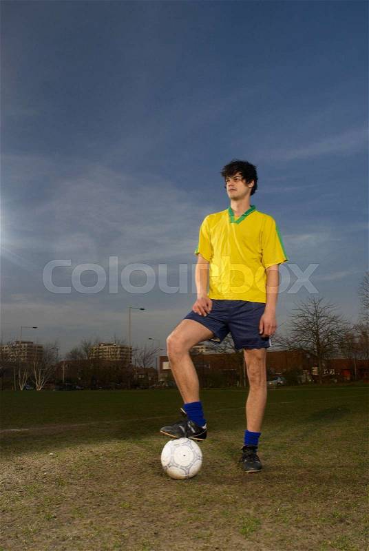 Footballer standing with ball, stock photo