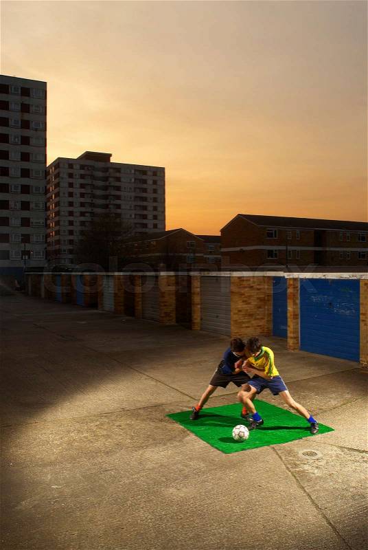 Footballers playing by garages, stock photo