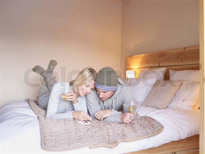 Woman and man lying on bed eating, stock photo
