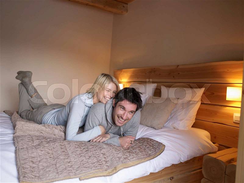 Woman and man lying on bed playing, stock photo