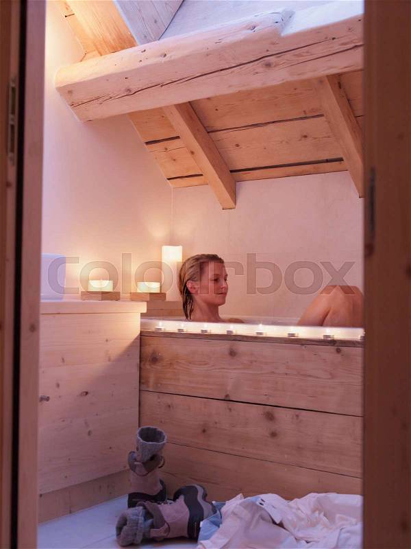 Woman sitting in bath tub, stock photo