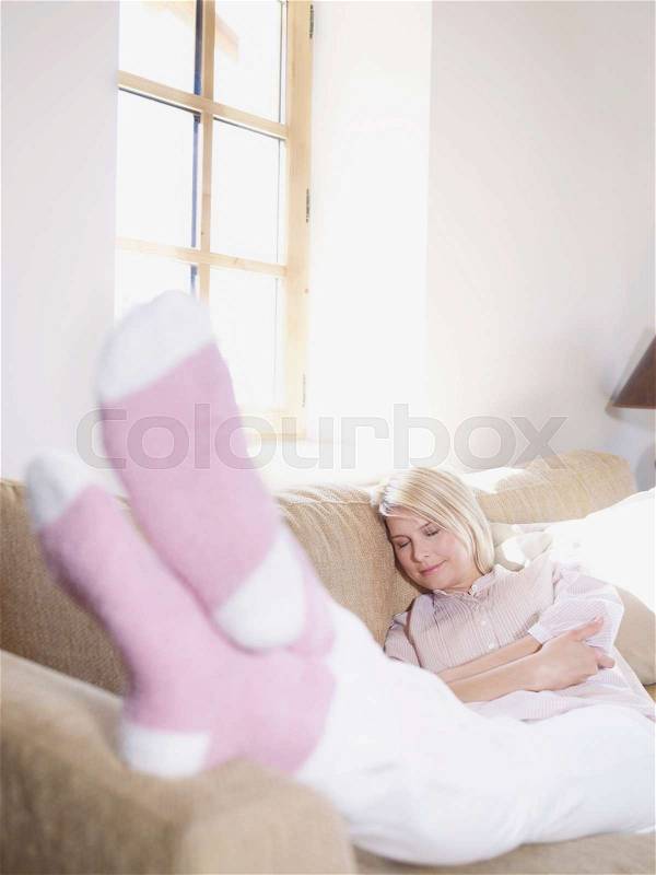 Woman relaxing, feet up in living room, stock photo
