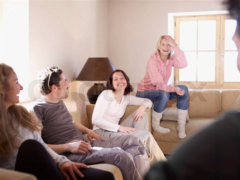 Friends laughing in chalet living room, stock photo