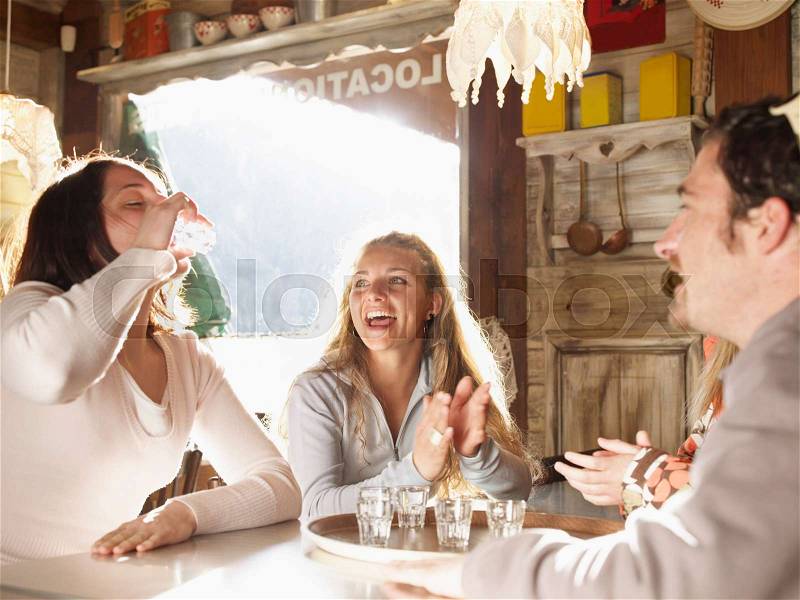Friends laughing in ski lodge bar, stock photo
