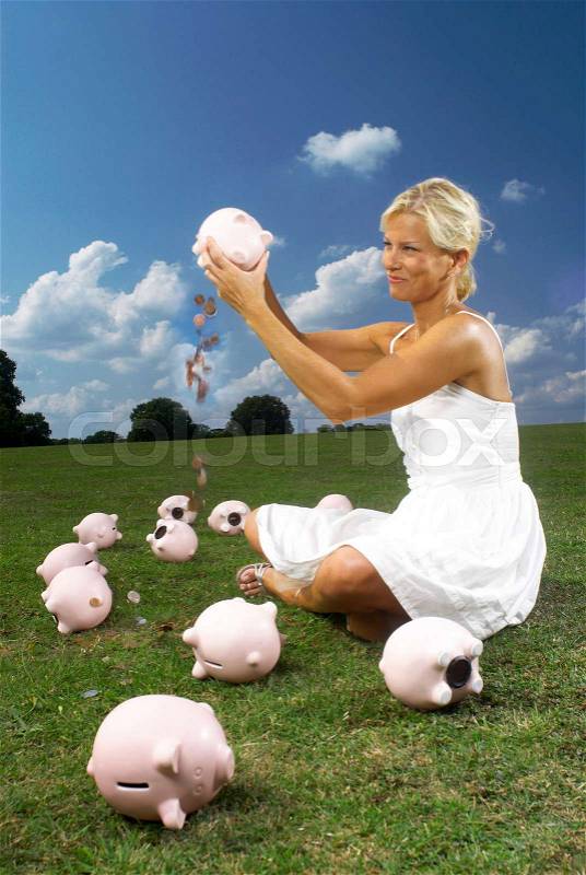 Woman shaking piggy bank, stock photo
