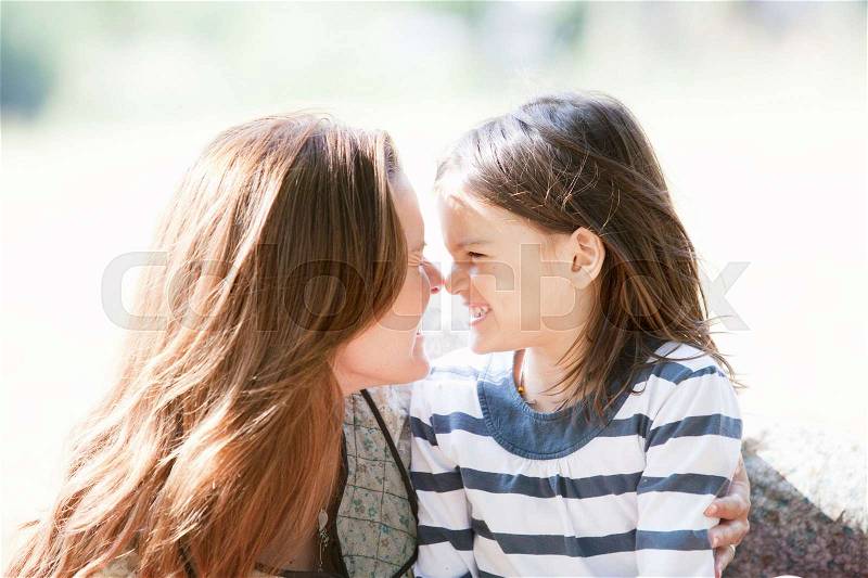 Mother and daughter smiling touch noses, stock photo