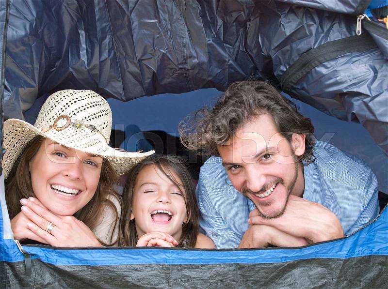 Family lying inside tent laughing, stock photo