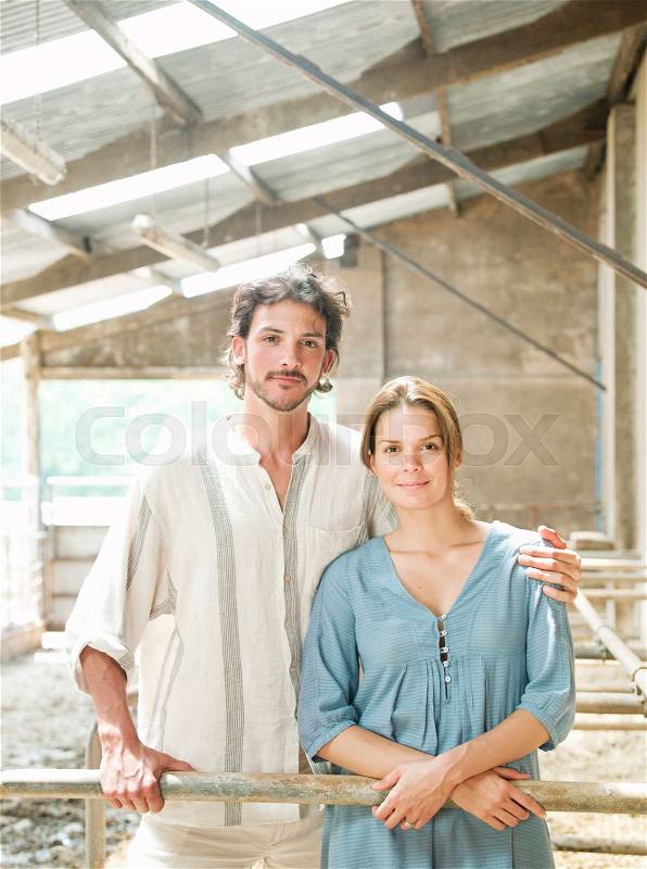 Man and woman standing in cattle shed, stock photo