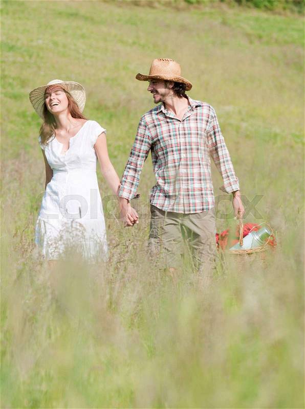 Couple in hats walking through meadow, stock photo
