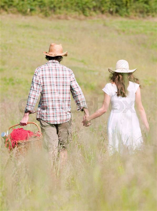 Couple in hats walking through meadow, stock photo