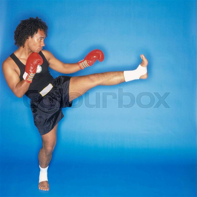Man doing front kick, side view, stock photo
