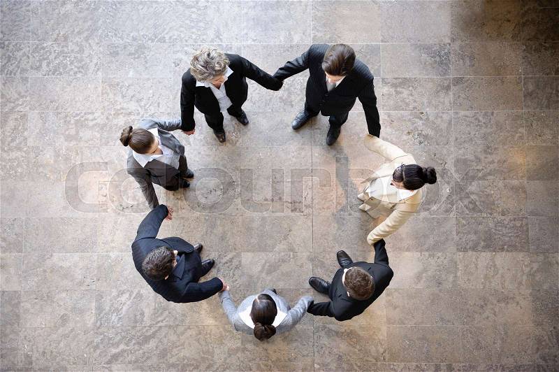 Business people holding hands in circle, stock photo
