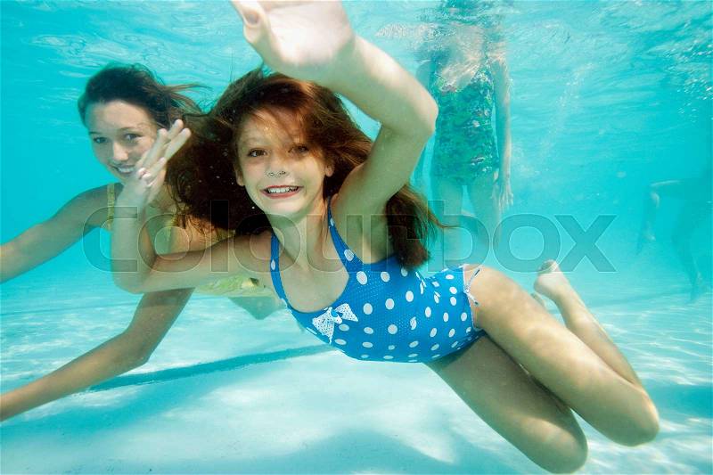 Girl underwater, smiling towards camera, stock photo