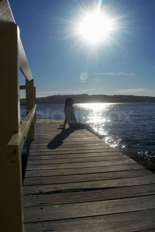 Woman relaxing by boat house, stock photo