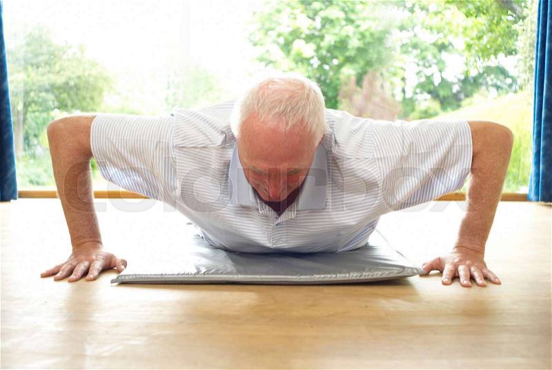 Older man doing pushups indoors, stock photo