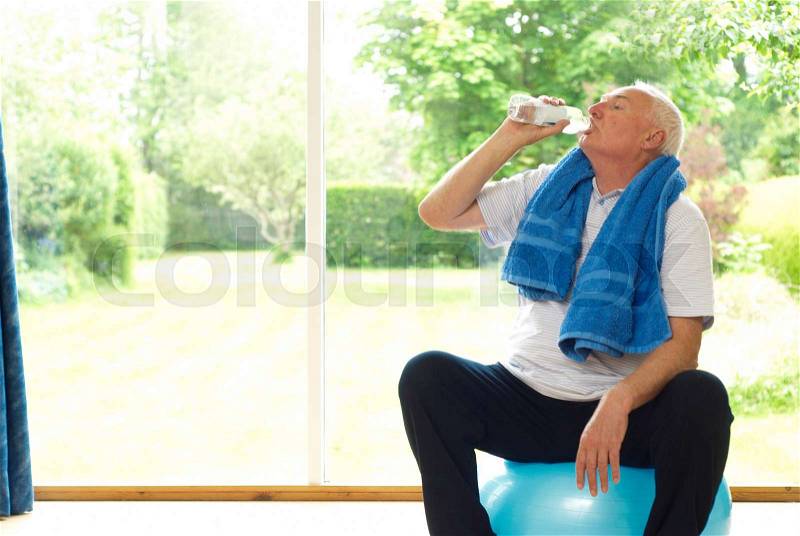 Older man drinking water during exercise, stock photo