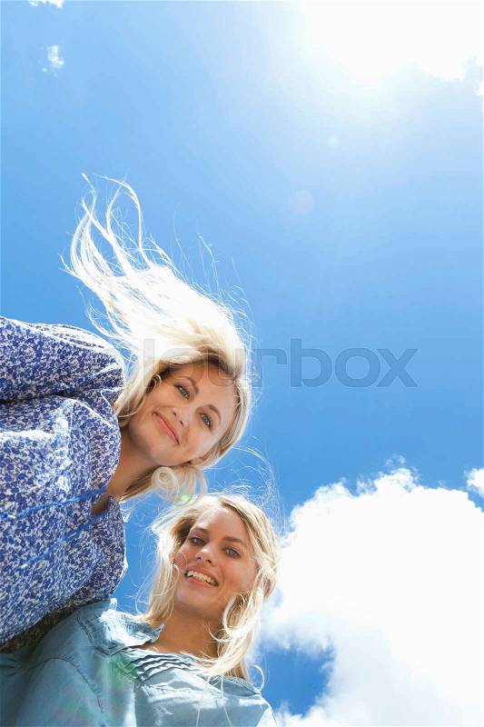 Low angle view of sisters hugging, stock photo