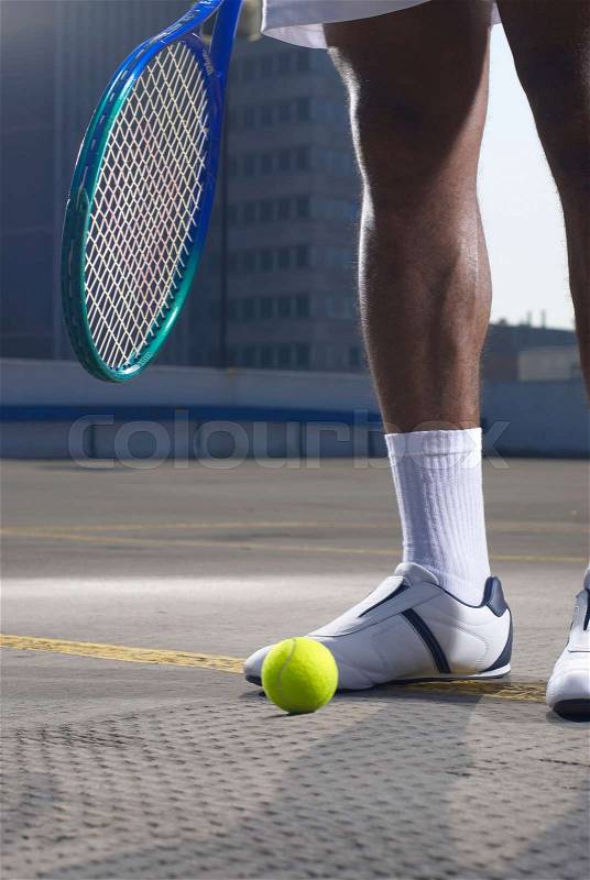 Tennis player with ball on rooftop court, stock photo