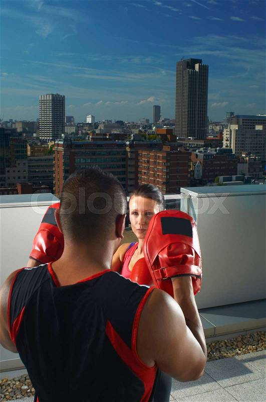Woman boxing with coach on rooftop, stock photo