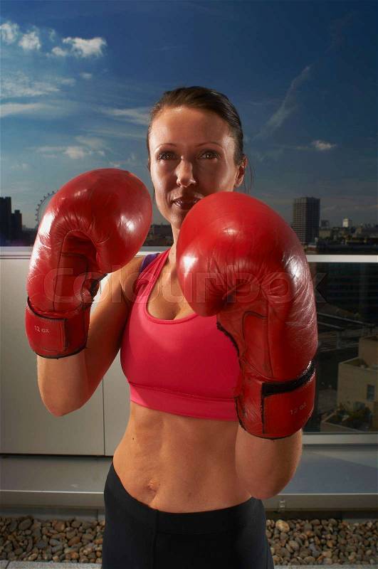 Boxer wearing gloves on urban rooftop, stock photo