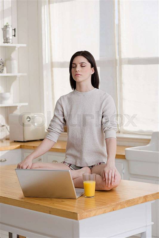 Meditating woman with laptop, stock photo