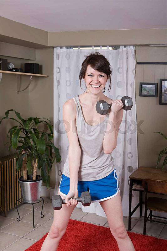 Young woman lifting hand weights, stock photo