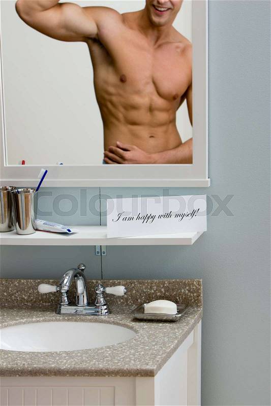 A happy young man looking in a mirror, stock photo