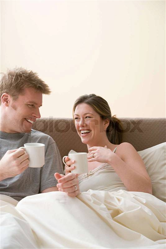 Happy couple having coffee in bed, stock photo