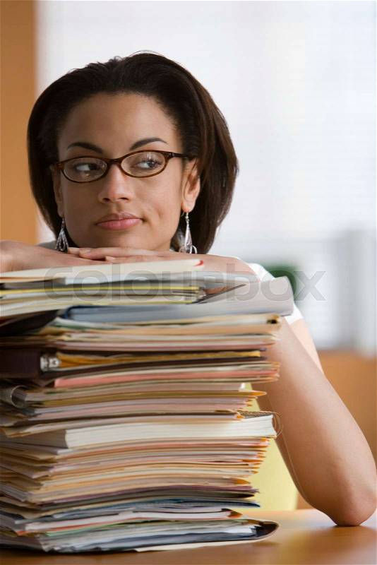 Young woman leaning on stack of files and paperwork, stock photo