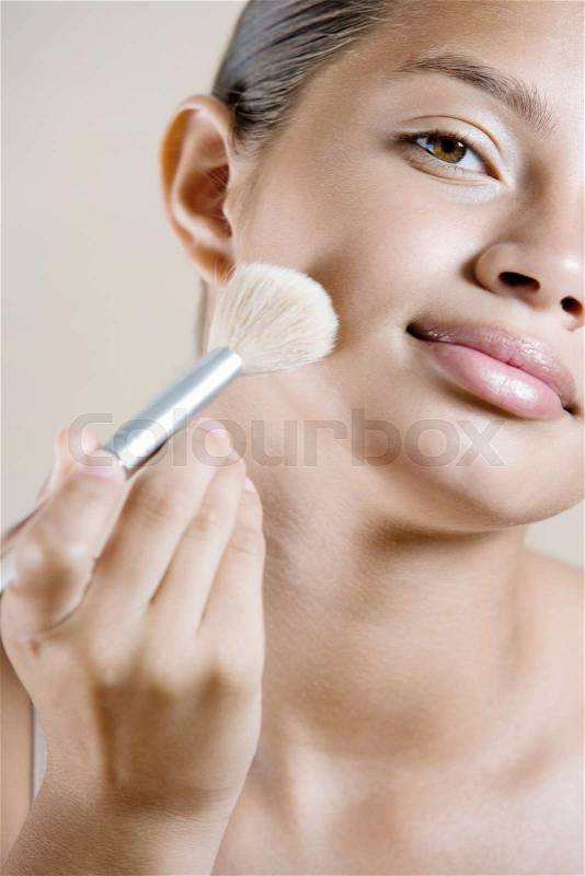 Girl applying face powder, stock photo