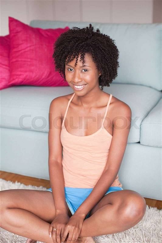 Young woman sitting on floor with legs crossed, stock photo