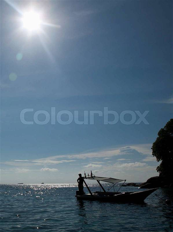 Man standing on docked boat in sunlight, Tioman Island, Malaysia, stock photo