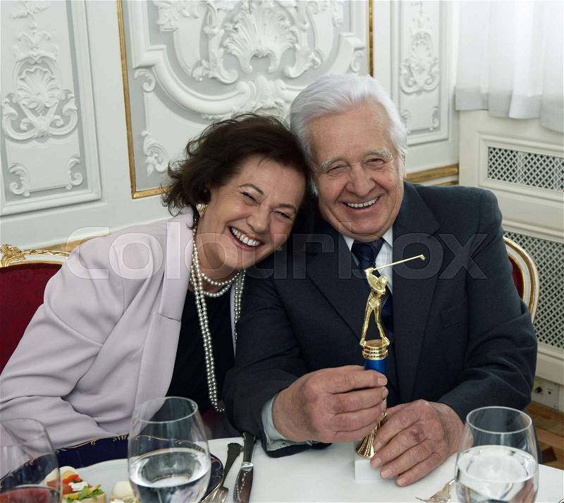 Senior couple with golf trophy smiling, stock photo