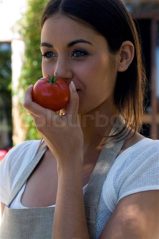 Young woman smelling fresh tomatoes, stock photo