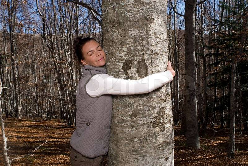 Woman taking a tree in her arms, stock photo