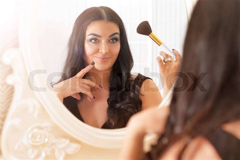 Portrait of a young attractive woman doing make up, stock photo
